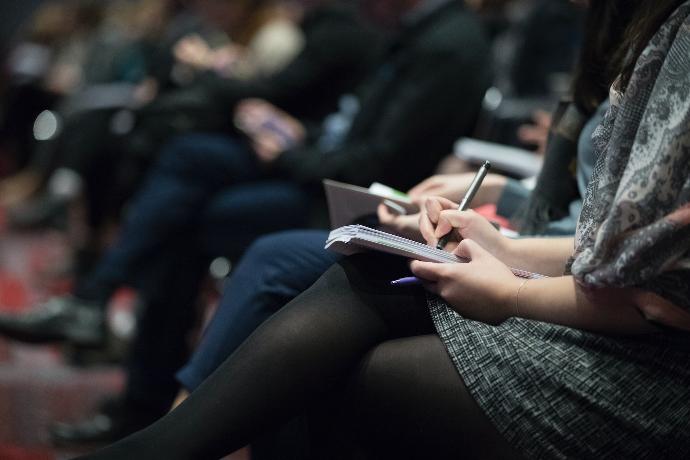 selective focus photography of people sitting on chairs while writing on notebooks